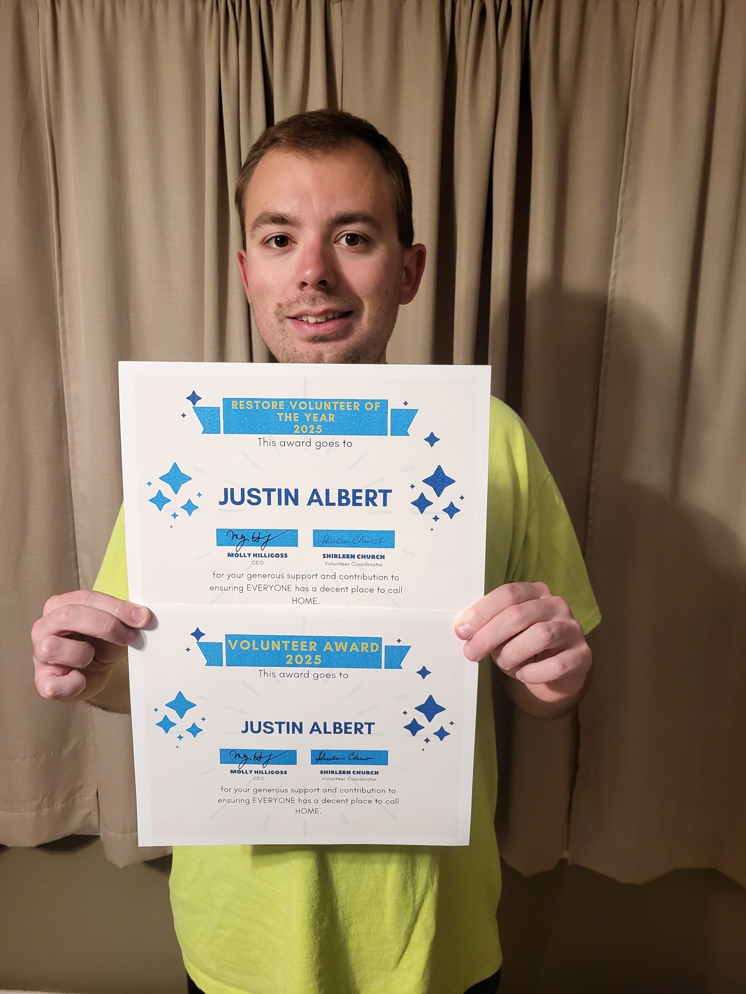 Volunteer Justin Albert Volunteer of the Year certificates and smiling.